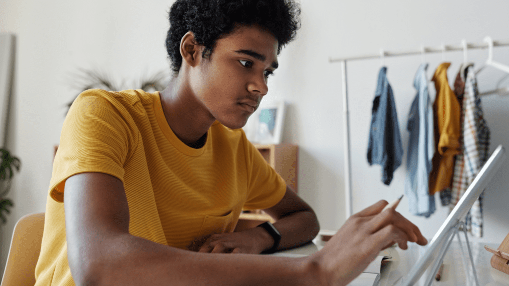 A male presenting young adult interact with a computer to optimize YouTube videos for search